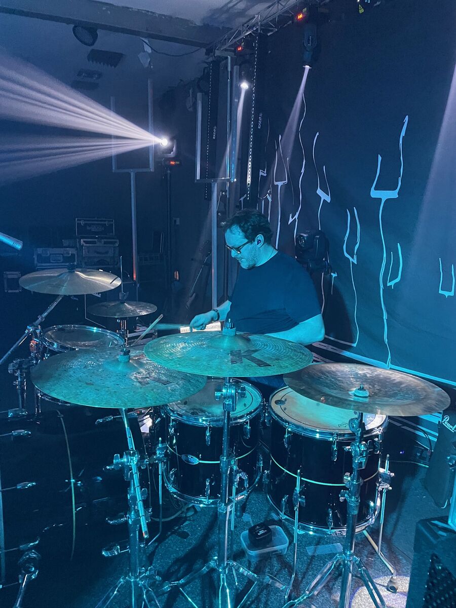 Drummer performing with blue lighting and stage effects